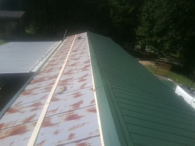 Old rusted panels beside newly installed green metal roofing — Wind Damage Roof Repair by Roofing Brothers in Dallesport