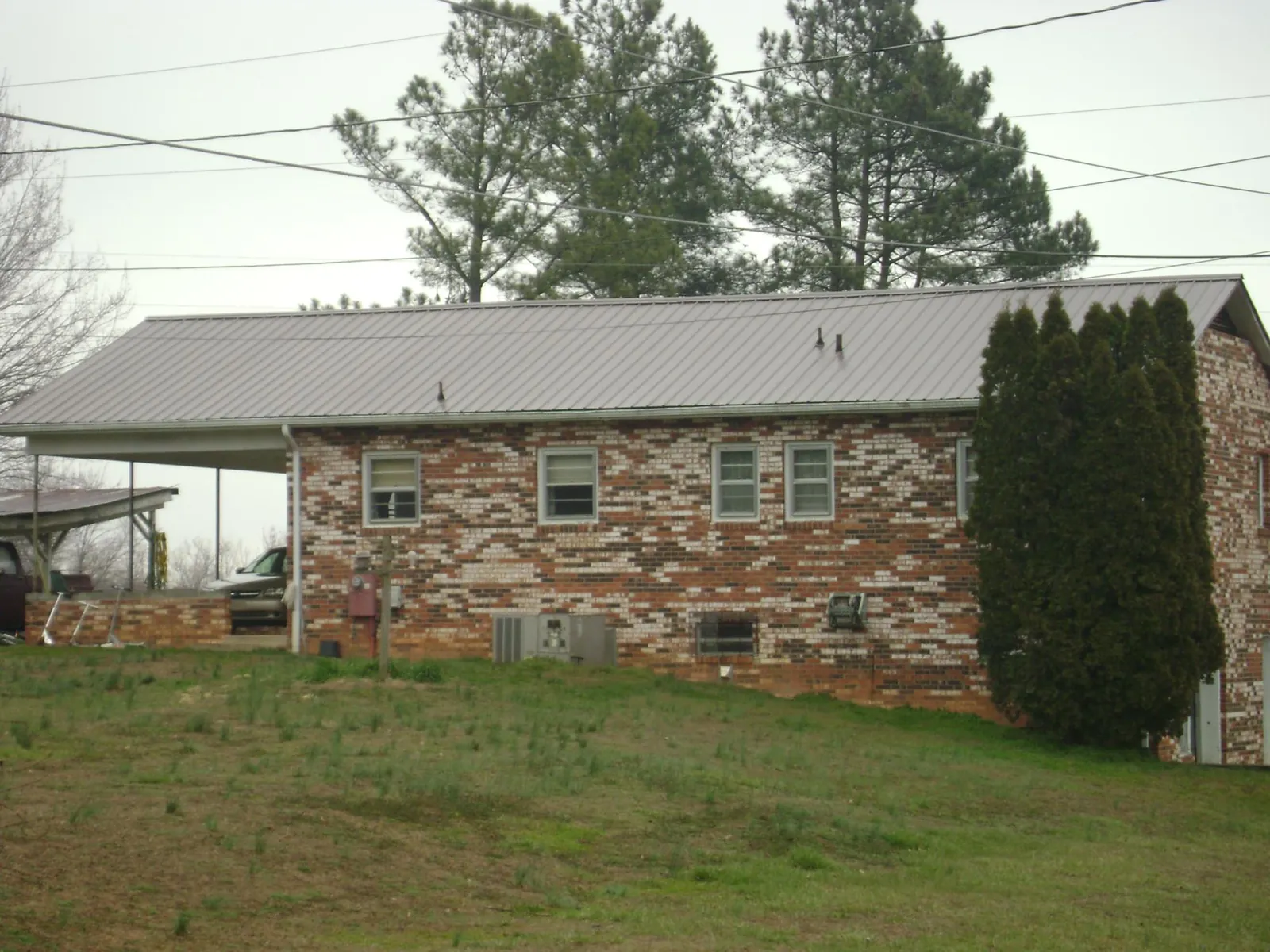 Gray metal roof on a brick split level home with a carport in Dallesport