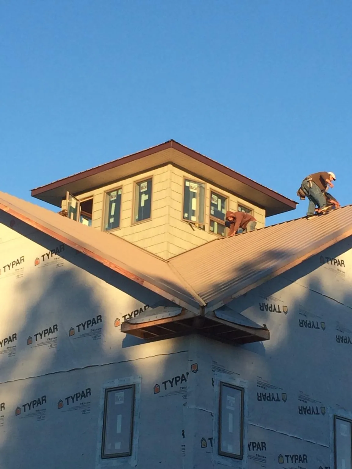 Roofers working around a rooftop cupola on a new metal roof at sunset — Roof Waterproofing in Dallesport by Roofing Brothers